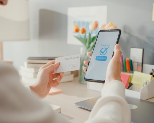 Closeup young asia lady use cellphone order online shopping product and pay bills with credit card in living room interior at house, Self quarantine activity, Fun activity for coronavirus prevention.